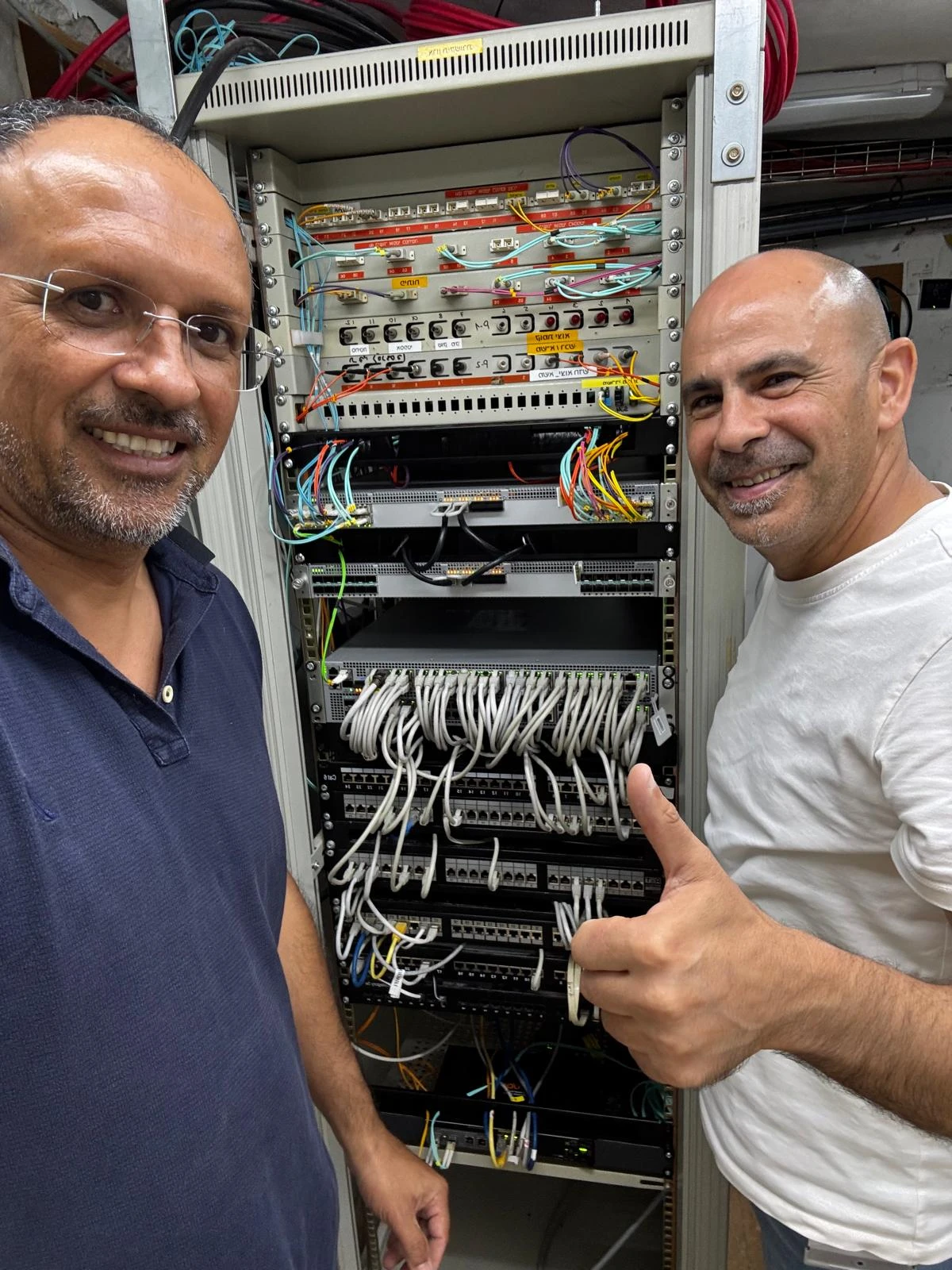 אלירן מפריגת ואלכס מ‑ILS מול ארון התקשורת ומתגי הליבה באתר